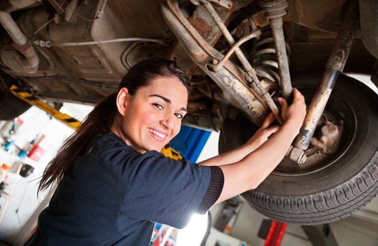 a woman technician working under a car