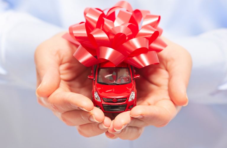 image of a person's hands holding a toy car wrapped in ribbon