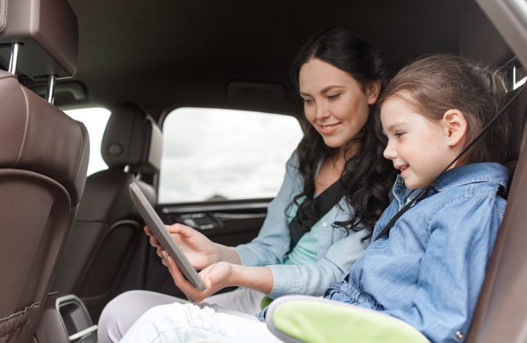 a woman and a young girl in the backseat of a car