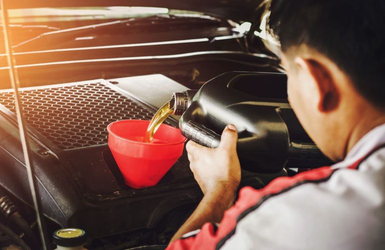 Technician pouring oil in a funnel