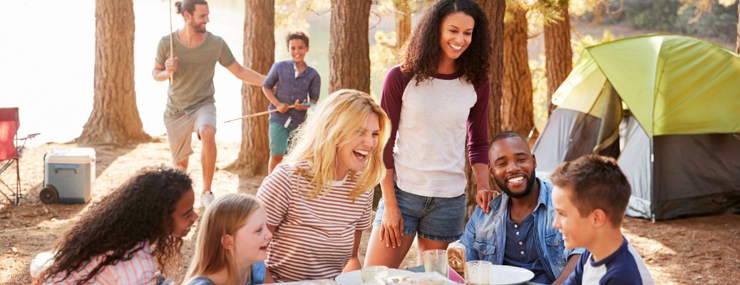 People sitting and standing together at a campsite