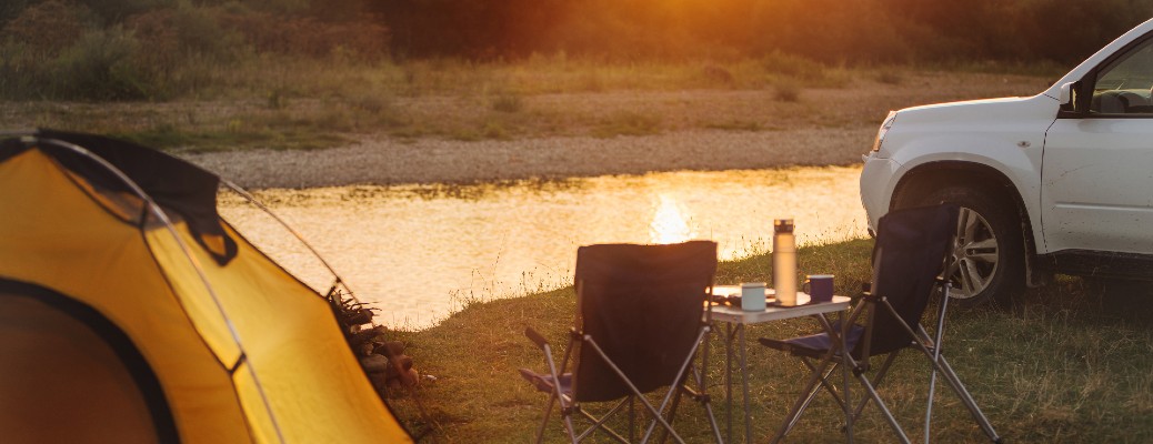 a campsite by a river with a truck and tent