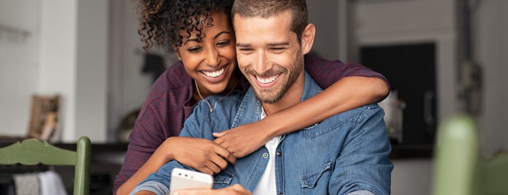 two happy people using a white phone