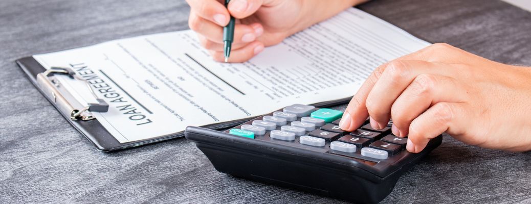 two hands using a calculator and signing a paper