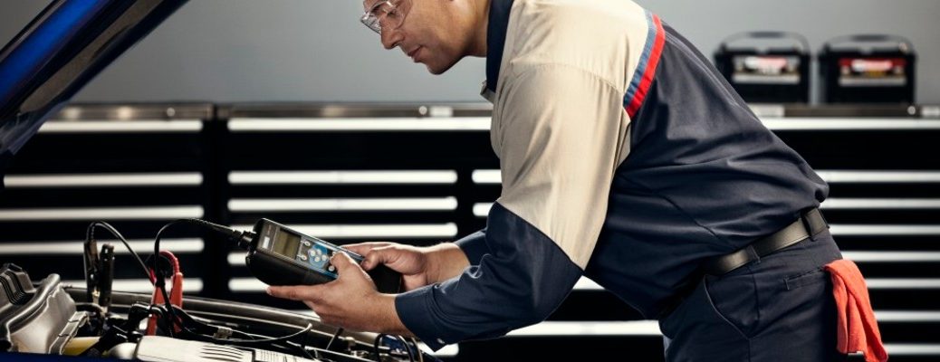 Ford mechanic checking car battery in service bay