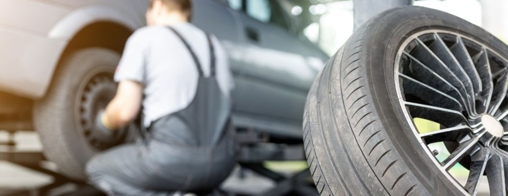 a man in overalls swapping a car tire