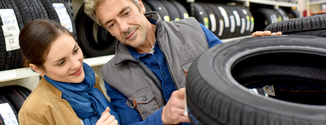 A man and a woman smiling at a car tire