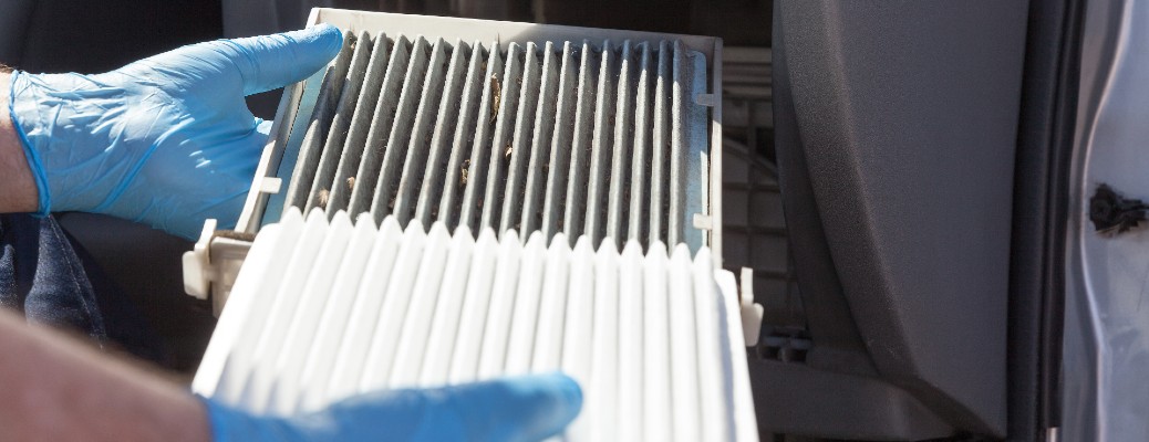 two gloved hands holding a car air filter