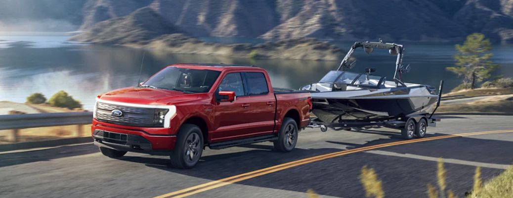 2023 Ford F-150 Lightning towing a boat on a road