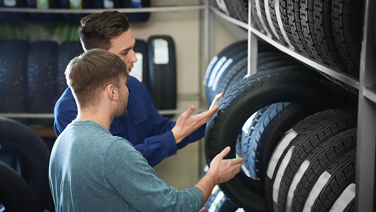 Two men inspecting a rack of tires