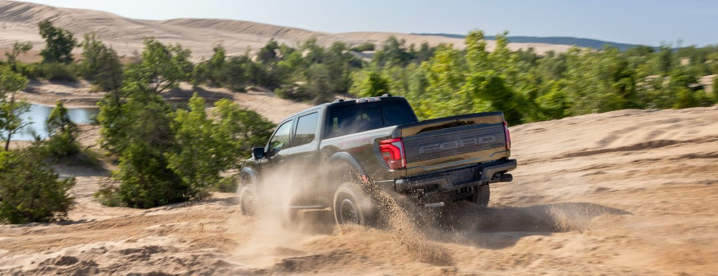 2024 Ford F-150 Raptor rear view driving down a hill