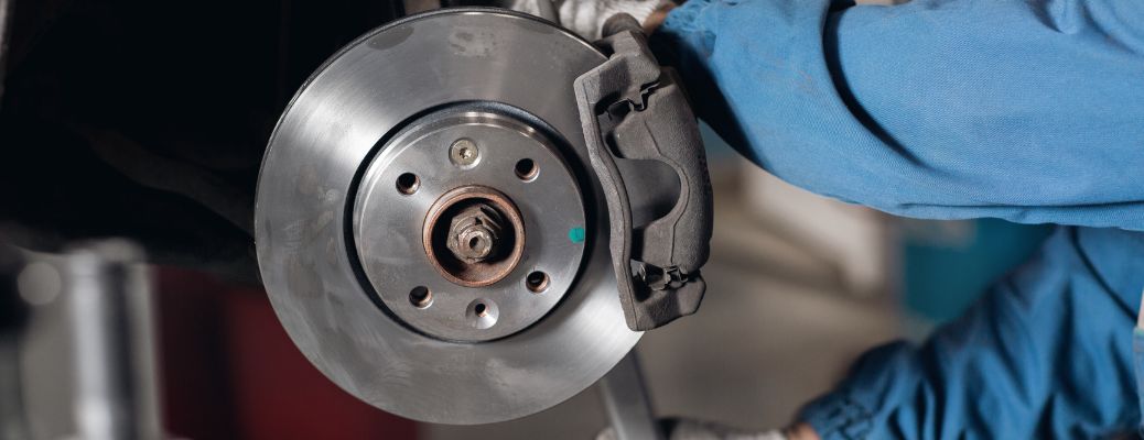 blue-suited worker working on car brakes