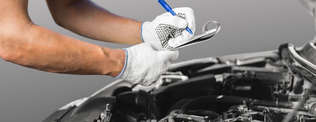 two white-gloved hands writing on a clipboard over a car
