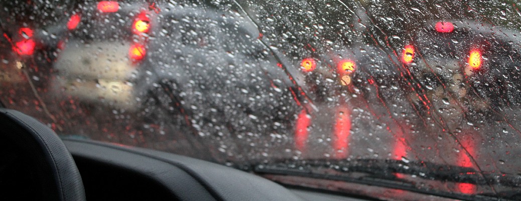 a rainy windshield with brake lights showing through