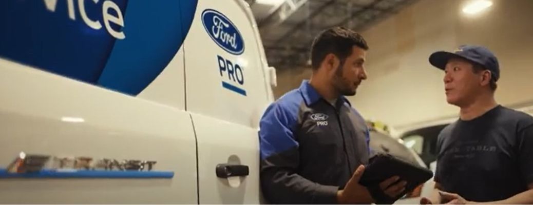 Ford Pro van with two people standing next to it