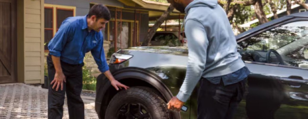Two people looking at the tire of a vehicle
