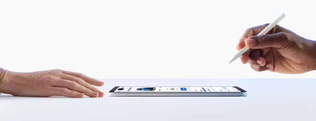 two hands over a white table signing a form