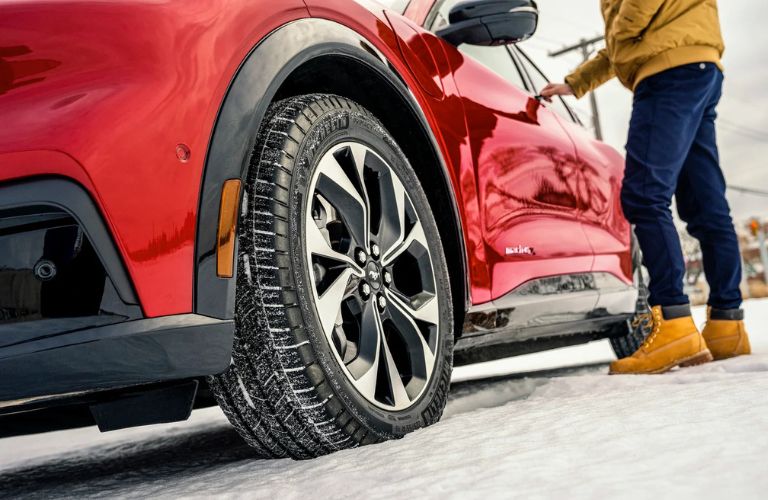 a person standing in the snow by a red vehicle