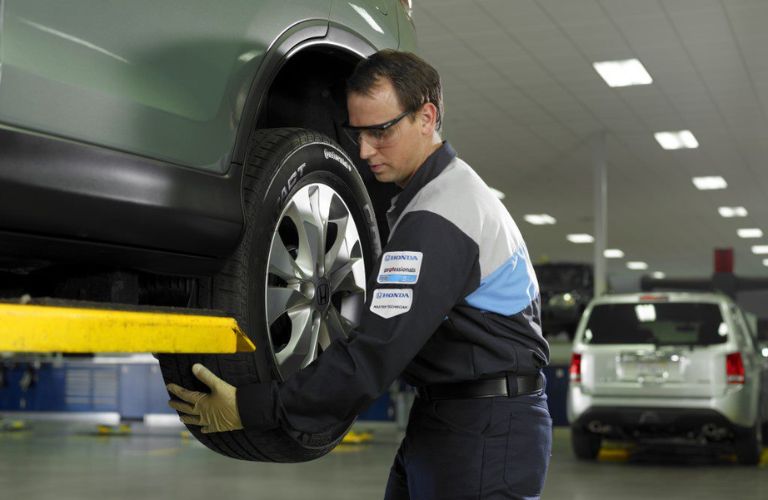 Mechanic Checking Tires of a Vehicle