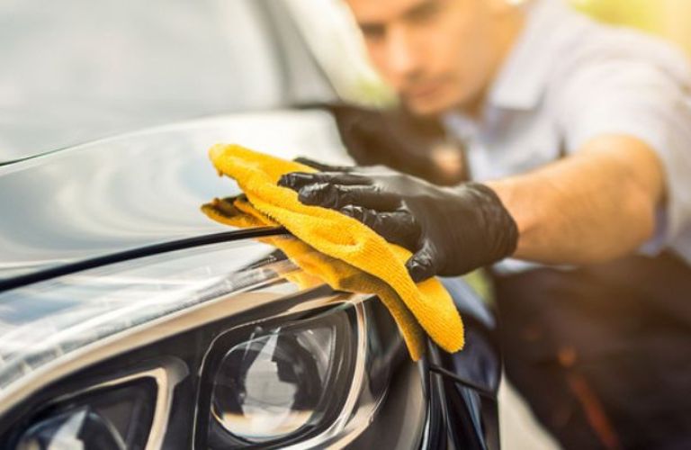 close up of a technician cleaning a car's headlight
