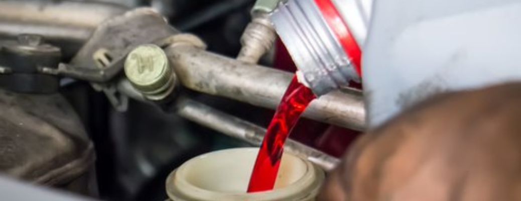 close up of a technician pouring fresh transmission fluid in a car