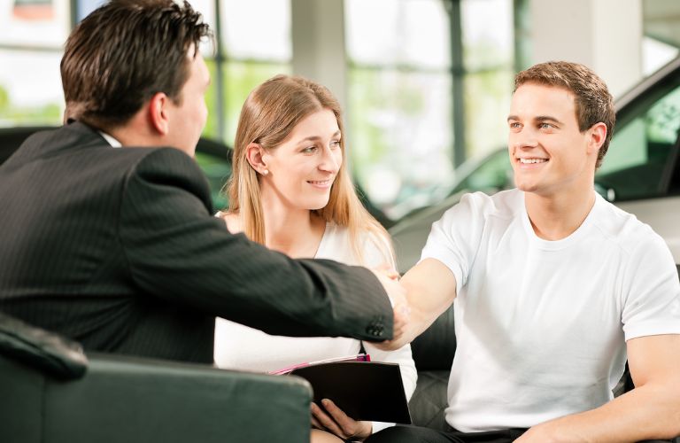 a salesman shaking hand with a buyer at a dealership