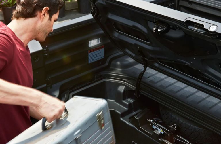 a man putting luggage in the 2026 Honda Ridgeline