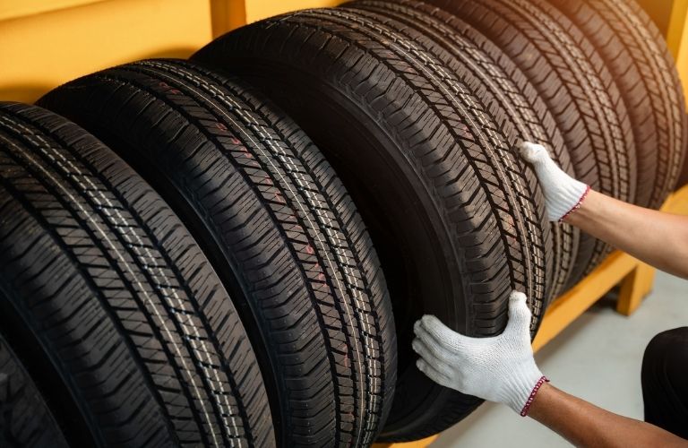 a technician wearing gloves pulling out a fresh tire