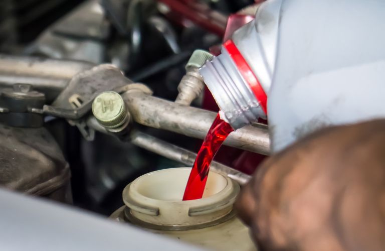 A mechanic pouring transmission fluid