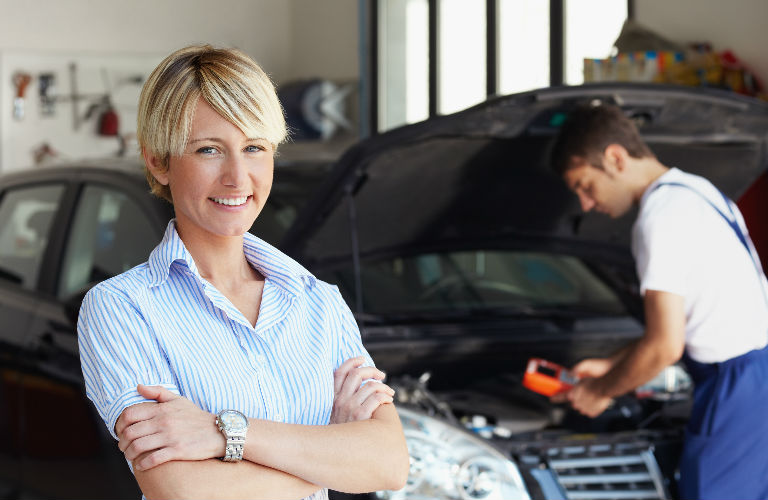 Technician inspecting a vehicle and a customer smiling