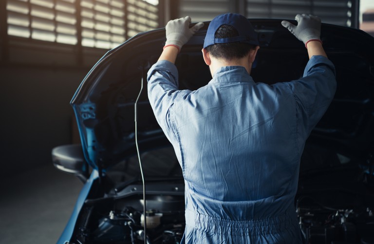 Technician looking under the hood of a vehicle
