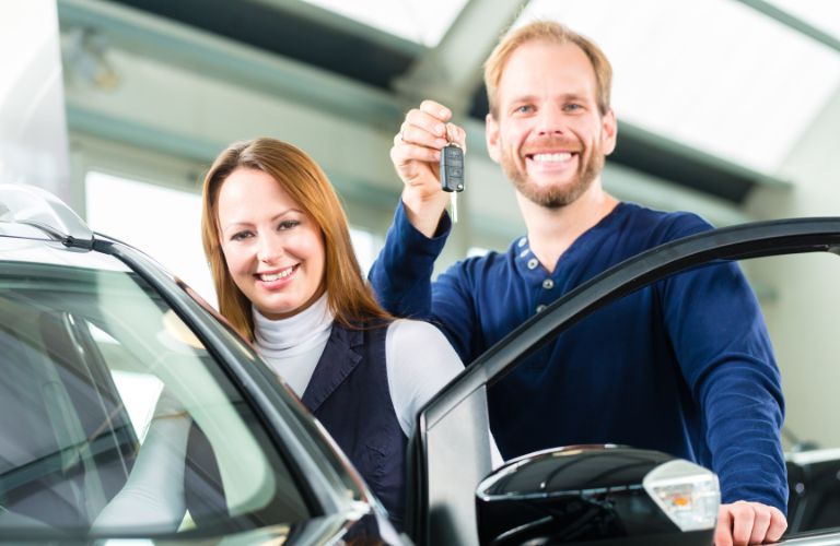 couple showing key as they get into a car