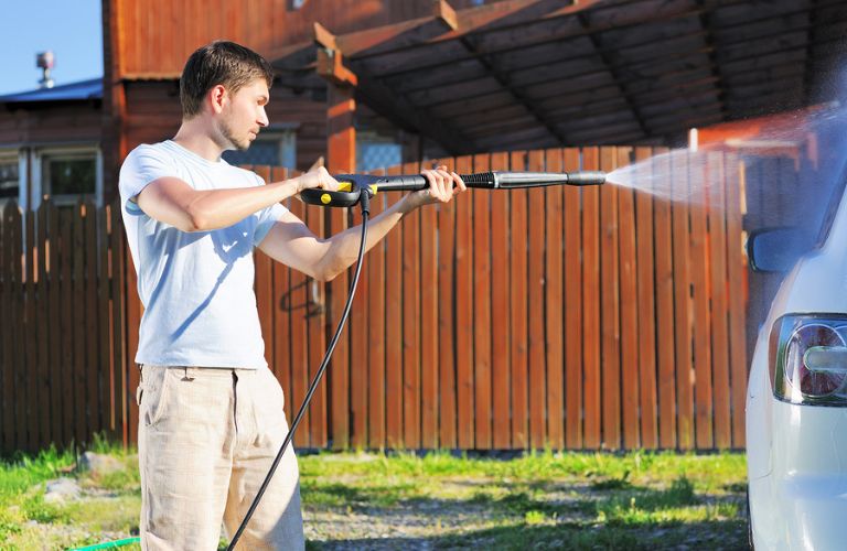 Man washing a car with a water pump