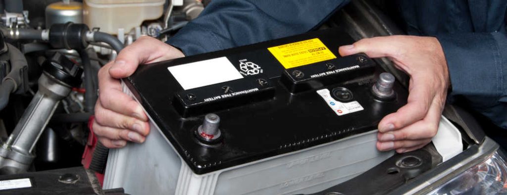A car mechanic replaces a battery in a car that has been damaged by the heat in Puerto Rico.