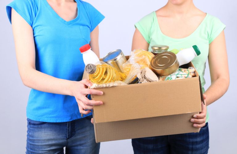 Women holding a box filled with food