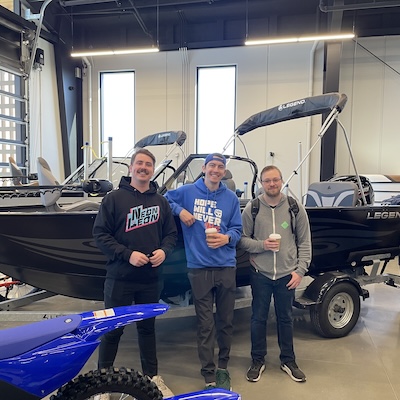 three people posing with a boat at Sherwood Powersports & Marine grand opening