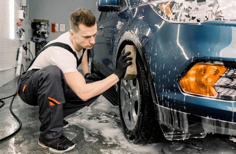 Mechanic cleaning wheel of car