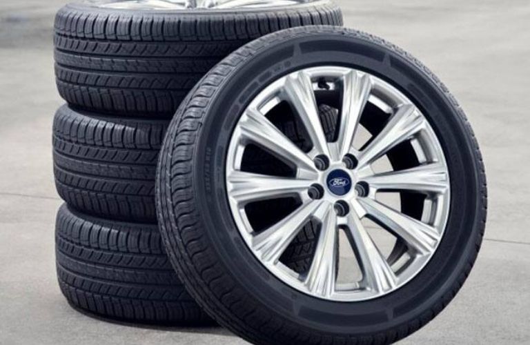 three Ford tires vertically on top of one another and one tire vertically standing with their support