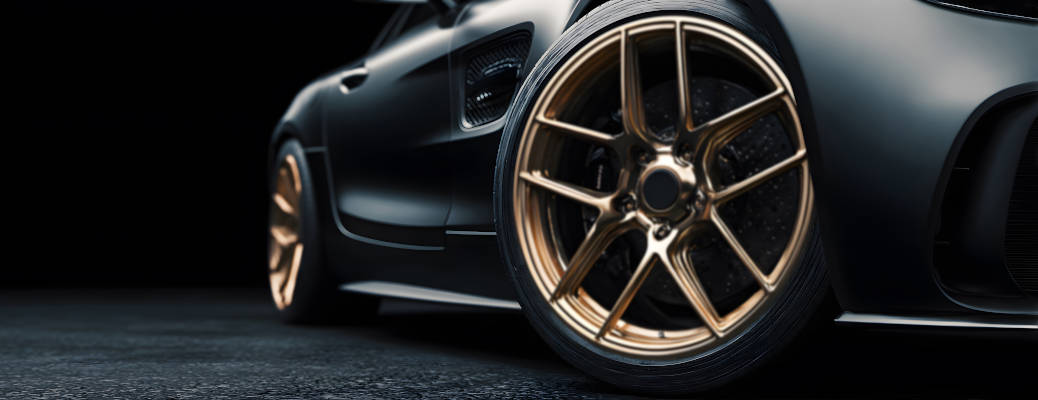 close-up of a gold rim luxury supercar wheel isolated against a dark background, captured in black and white banner format with room for copy, emphasizing automotive design and modern performance