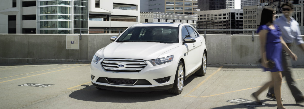 Front view of the 2017 Ford Taurus and a couple walking past it