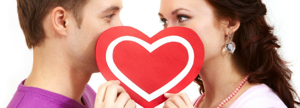 man and a woman holding a paper heart up to cover their mouths