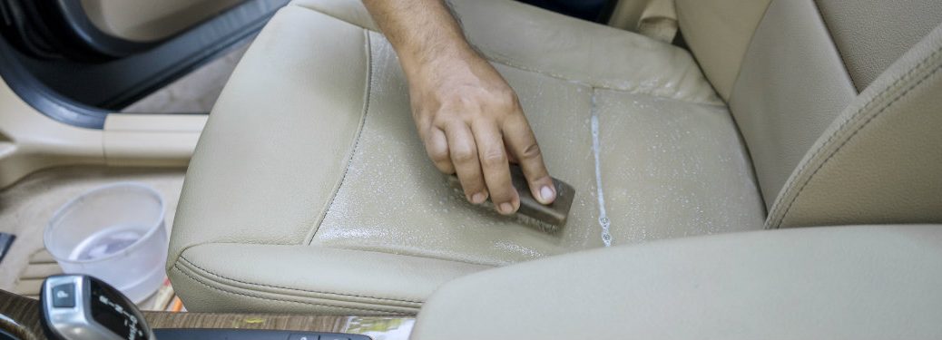 person scrubbing the seat of a car, only the hand visible