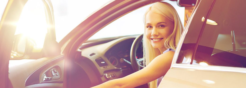 girl smiling in a car holding the door open