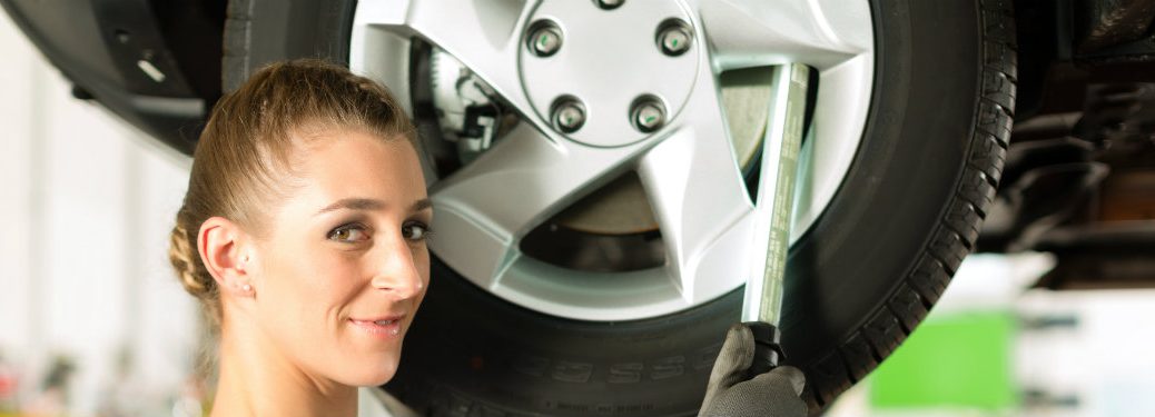 female mechanic with her face by a wheel (car on a lift)