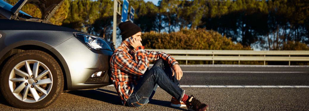 young man with a broken car calling someone