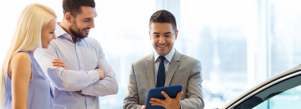 Car salesman assisting couple in buying a car.