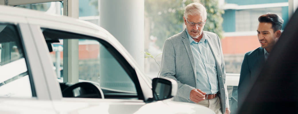 Car dealership, choice or salesman with customer talking for vehicle history, details or features. Transport, people or person with client in showroom for negotiation, report or decision for purchase