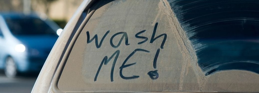 Back window of vehicle with dust and wash me! written on it