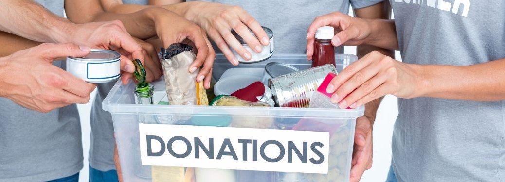Volunteers standing around donations box with food items in it