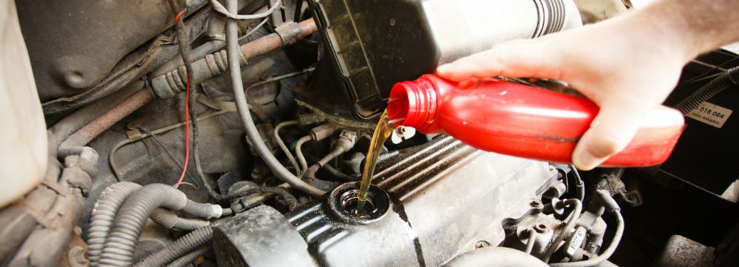 person pouring oil into a vehicle engine